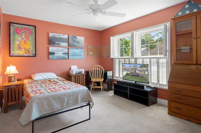 bedroom featuring ceiling fan, light carpet, and a textured ceiling