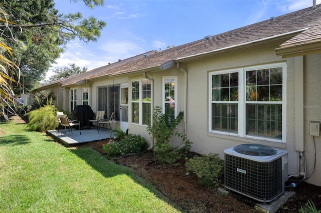 rear view of property with central AC and a yard