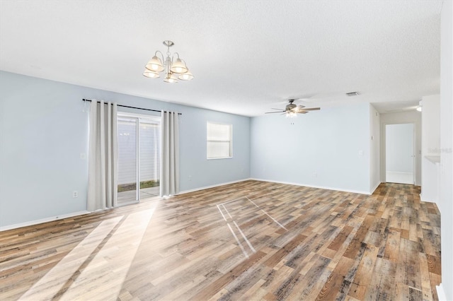 empty room with wood-type flooring, ceiling fan with notable chandelier, and a textured ceiling