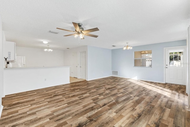 unfurnished living room with hardwood / wood-style floors, ceiling fan with notable chandelier, and a textured ceiling