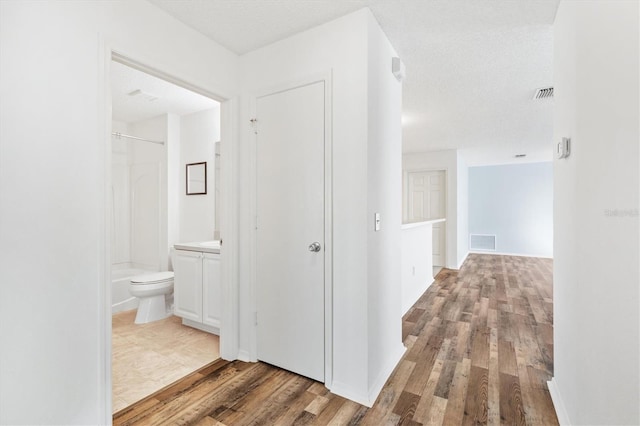 hall with wood-type flooring and a textured ceiling