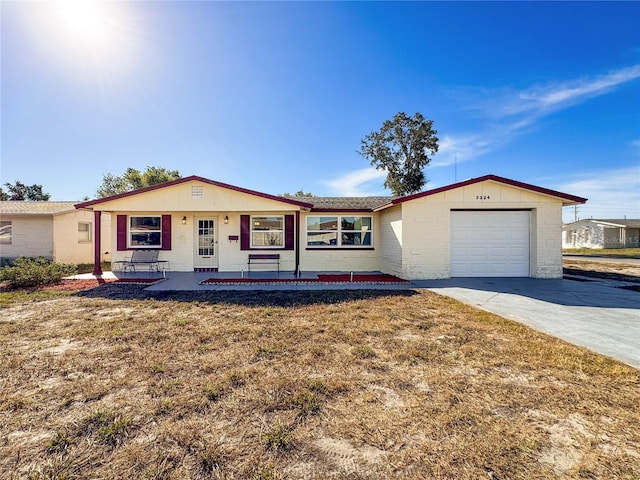 ranch-style home with covered porch, a garage, and a front yard