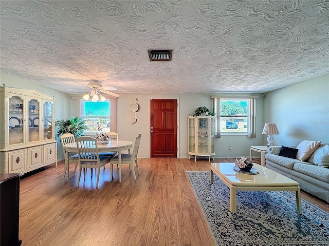 living room with ceiling fan, light hardwood / wood-style floors, and a textured ceiling