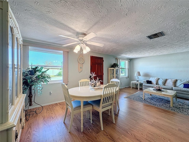 dining space featuring ceiling fan, light wood-type flooring, and a textured ceiling