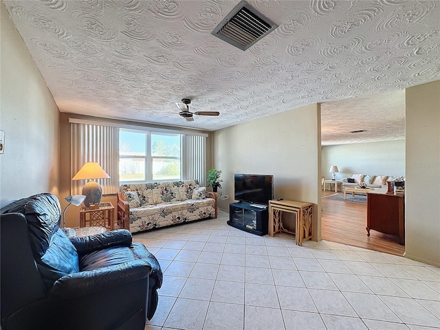 tiled living room with a textured ceiling and ceiling fan