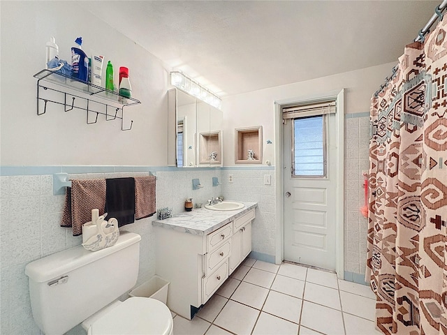 bathroom featuring toilet, vanity, tile patterned floors, and tile walls