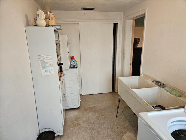 laundry room featuring a textured ceiling, washer / clothes dryer, and sink