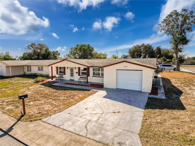 ranch-style home with a front lawn, central AC unit, a porch, and a garage