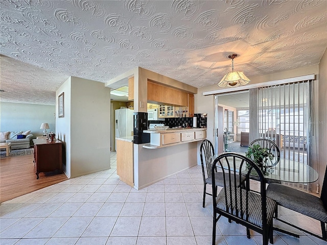 kitchen featuring white refrigerator with ice dispenser, light wood-type flooring, a textured ceiling, tasteful backsplash, and kitchen peninsula