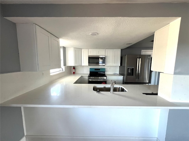 kitchen featuring sink, a textured ceiling, white cabinetry, kitchen peninsula, and stainless steel appliances