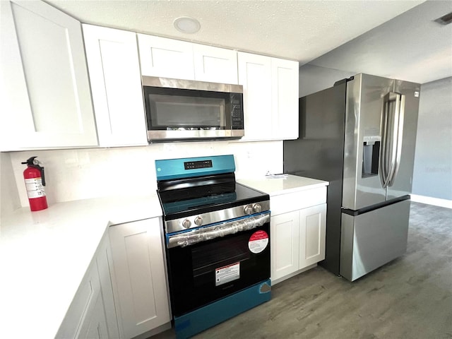 kitchen with appliances with stainless steel finishes, a textured ceiling, dark hardwood / wood-style floors, and white cabinetry