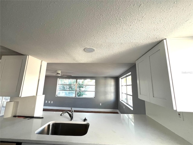 kitchen featuring white cabinetry, sink, ceiling fan, and a textured ceiling