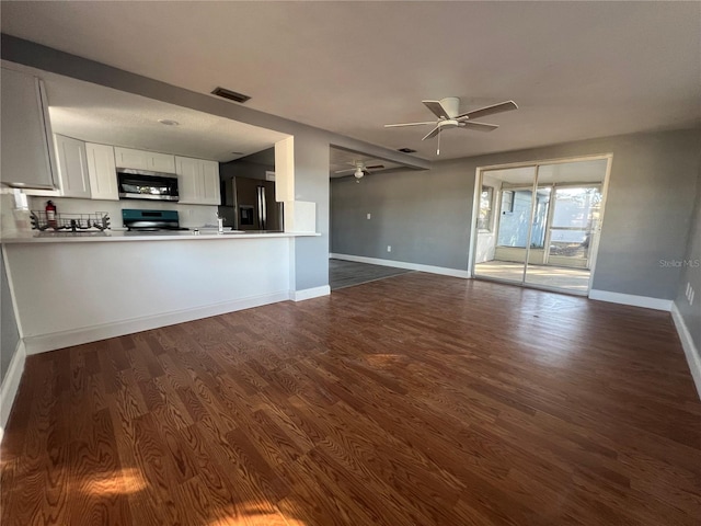 unfurnished living room featuring dark hardwood / wood-style flooring and ceiling fan