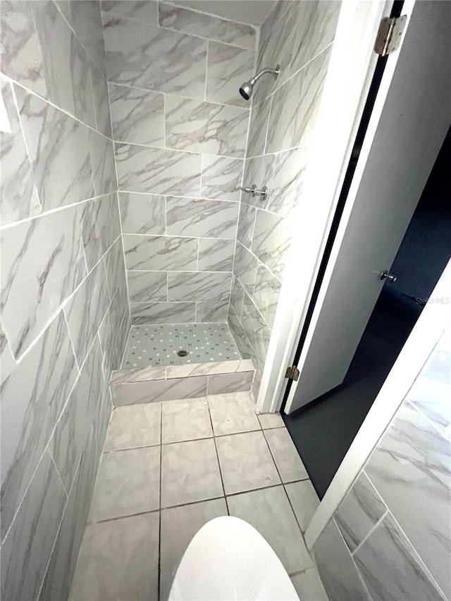 bathroom with a tile shower and toilet