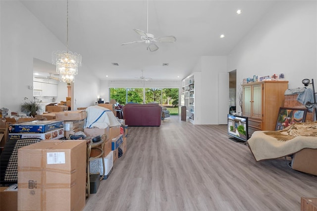 living room with light hardwood / wood-style floors, a towering ceiling, and ceiling fan