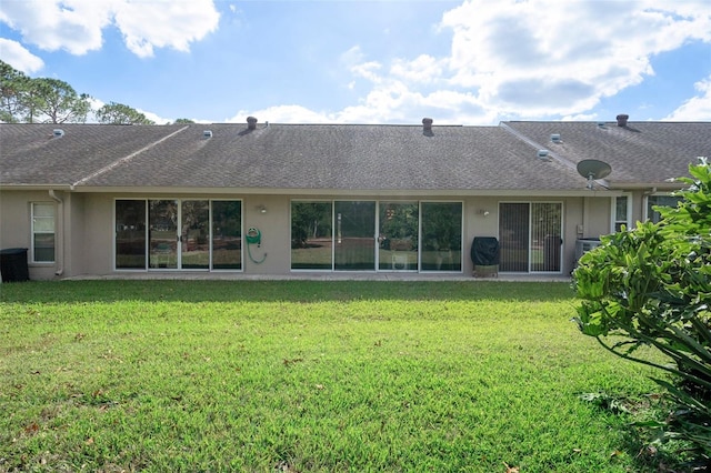 rear view of property with central air condition unit and a lawn