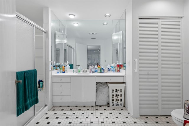 bathroom featuring a shower with door, toilet, vanity, and tile patterned flooring