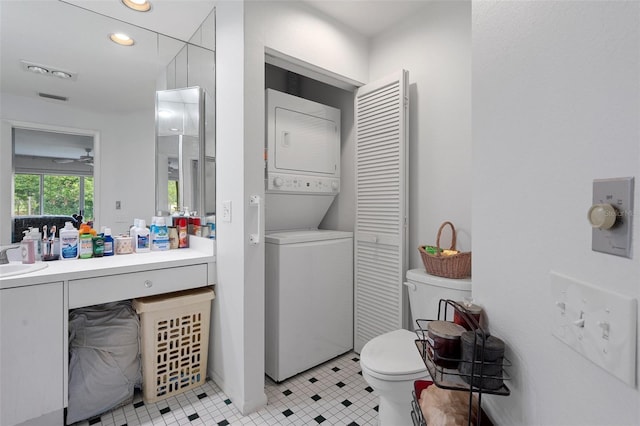 bathroom featuring stacked washer / dryer, toilet, tile patterned flooring, and vanity