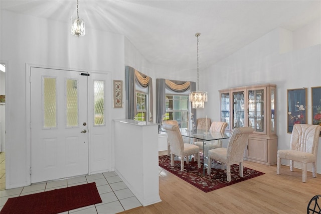 dining room featuring an inviting chandelier, high vaulted ceiling, and light wood-type flooring