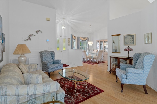 living room featuring wood-type flooring, high vaulted ceiling, and a notable chandelier