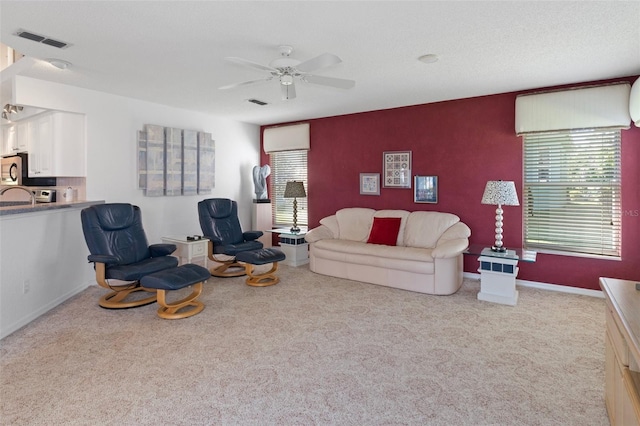 living room with ceiling fan, light colored carpet, and a wealth of natural light