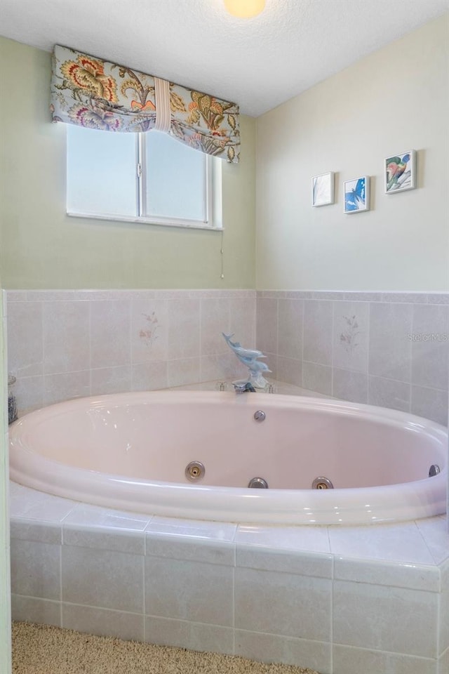 bathroom featuring a textured ceiling and tiled bath