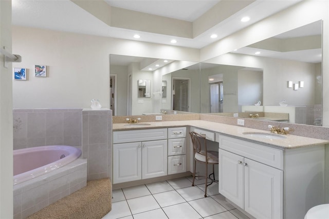 bathroom featuring tile patterned floors, vanity, and tiled bath