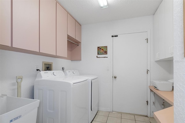 washroom with cabinets, a textured ceiling, sink, washer and dryer, and light tile patterned floors