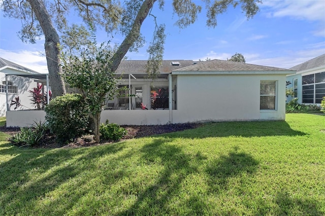 rear view of house with a yard and a lanai