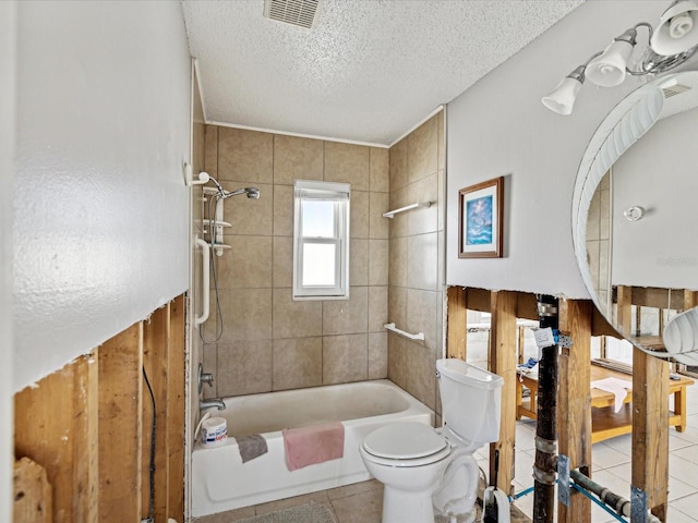 bathroom with tile patterned flooring, toilet, tiled shower / bath, and a textured ceiling