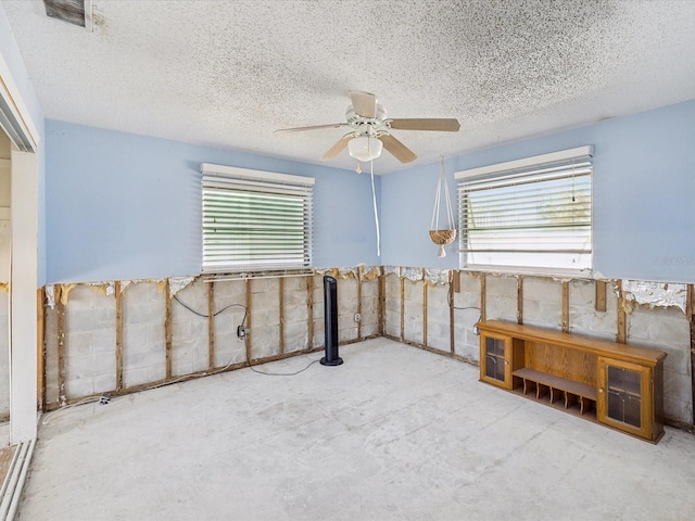 empty room featuring ceiling fan, plenty of natural light, and a textured ceiling