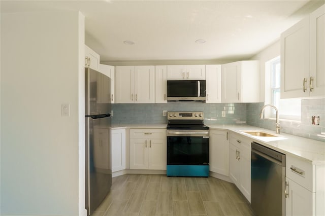 kitchen with white cabinets, backsplash, stainless steel appliances, and sink