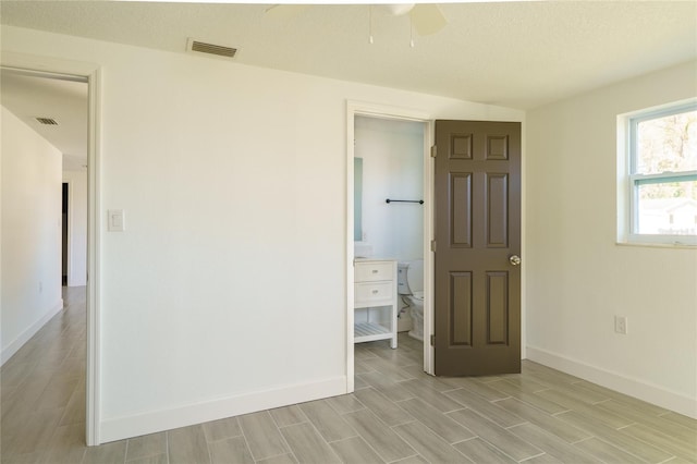 spare room with ceiling fan, light wood-type flooring, and a textured ceiling