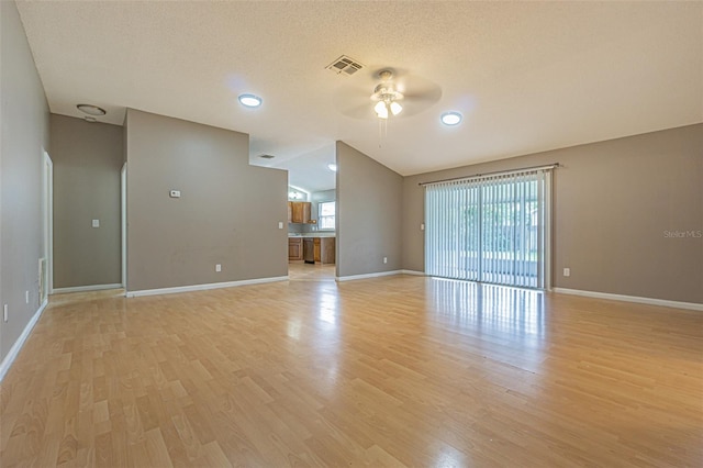 unfurnished living room with a textured ceiling, light hardwood / wood-style flooring, ceiling fan, and lofted ceiling