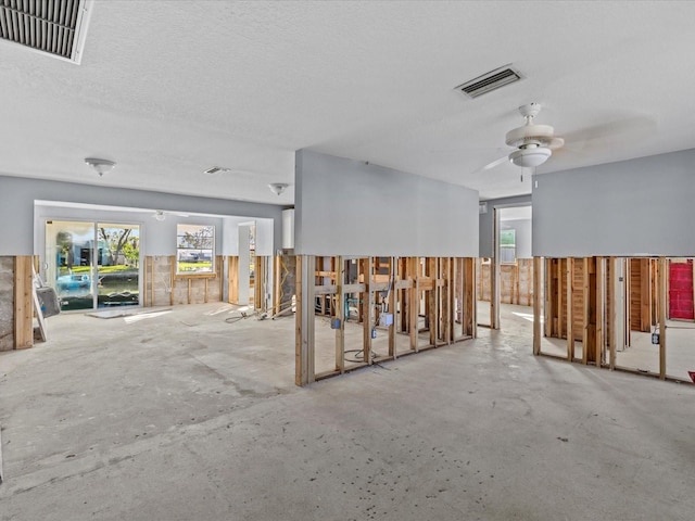 interior space featuring ceiling fan, concrete flooring, and a textured ceiling