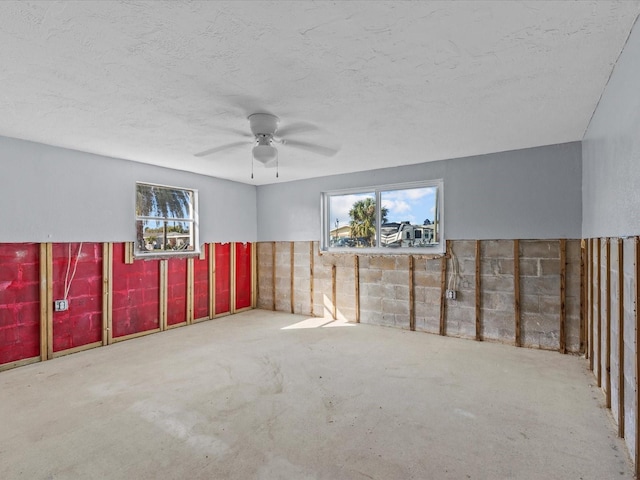 unfurnished room with a textured ceiling, a wealth of natural light, and ceiling fan