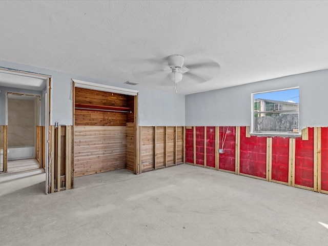 spare room with concrete floors, ceiling fan, and wooden walls