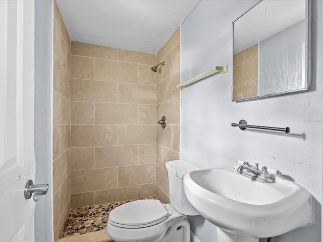 bathroom with toilet, sink, and tiled shower