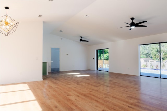 unfurnished living room featuring ceiling fan with notable chandelier, light hardwood / wood-style floors, and vaulted ceiling