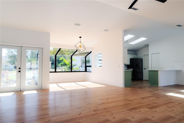 unfurnished living room with light hardwood / wood-style floors, high vaulted ceiling, and french doors