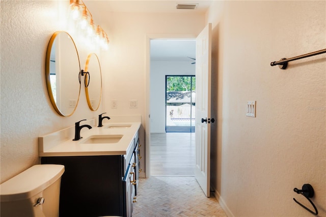 bathroom featuring parquet floors, vanity, and toilet