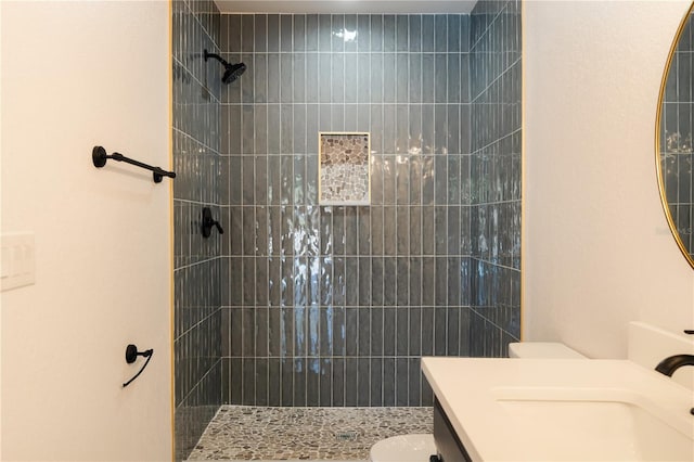 bathroom with a tile shower, vanity, and toilet