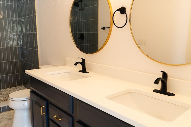 bathroom with tiled shower, vanity, and toilet