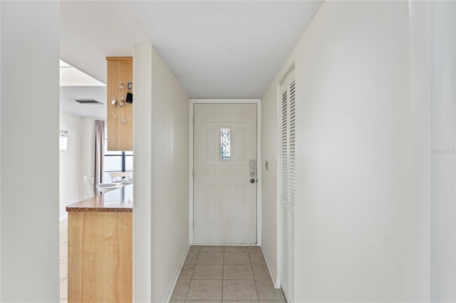 doorway with light tile patterned floors and a textured ceiling