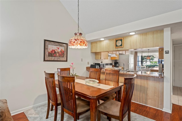 dining room featuring hardwood / wood-style flooring, lofted ceiling, and a textured ceiling