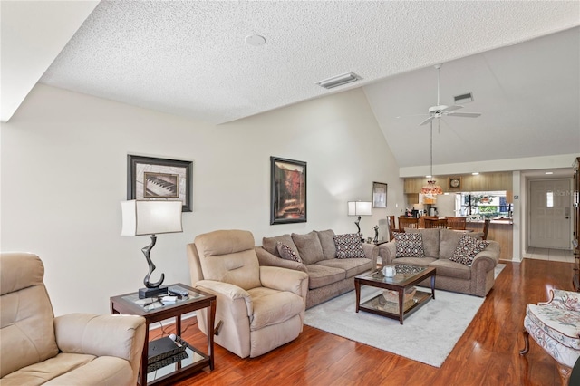 living room featuring ceiling fan, high vaulted ceiling, wood-type flooring, and a textured ceiling