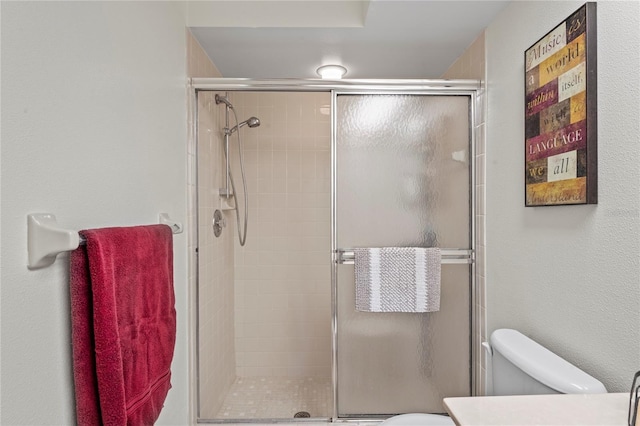 bathroom featuring toilet and a shower with door