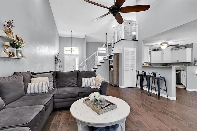 living room with ceiling fan, dark hardwood / wood-style flooring, and a high ceiling