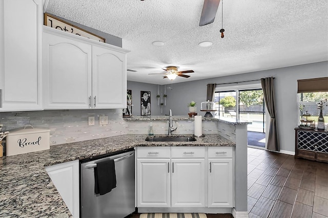 kitchen with white cabinets, sink, stainless steel dishwasher, dark stone countertops, and kitchen peninsula