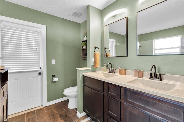 bathroom with vanity, a textured ceiling, hardwood / wood-style flooring, and toilet